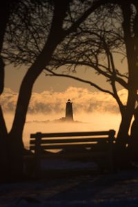 Preview wallpaper lighthouse, sunset, bench, blur, trees, branches