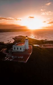 Preview wallpaper lighthouse, tower, building, pier, water, horizon, sunset