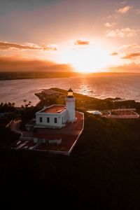 Preview wallpaper lighthouse, tower, building, pier, water, horizon, sunset