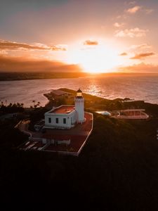 Preview wallpaper lighthouse, tower, building, pier, water, horizon, sunset