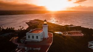 Preview wallpaper lighthouse, tower, building, pier, water, horizon, sunset