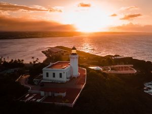 Preview wallpaper lighthouse, tower, building, pier, water, horizon, sunset