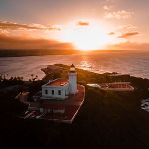 Preview wallpaper lighthouse, tower, building, pier, water, horizon, sunset
