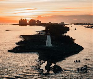 Preview wallpaper lighthouse, tower, island, sea, buildings, sunset
