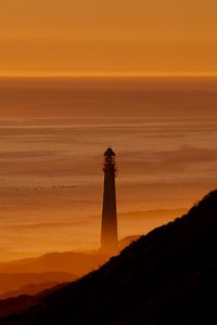 Preview wallpaper lighthouse, tower, sea, mountains, sunset, dark