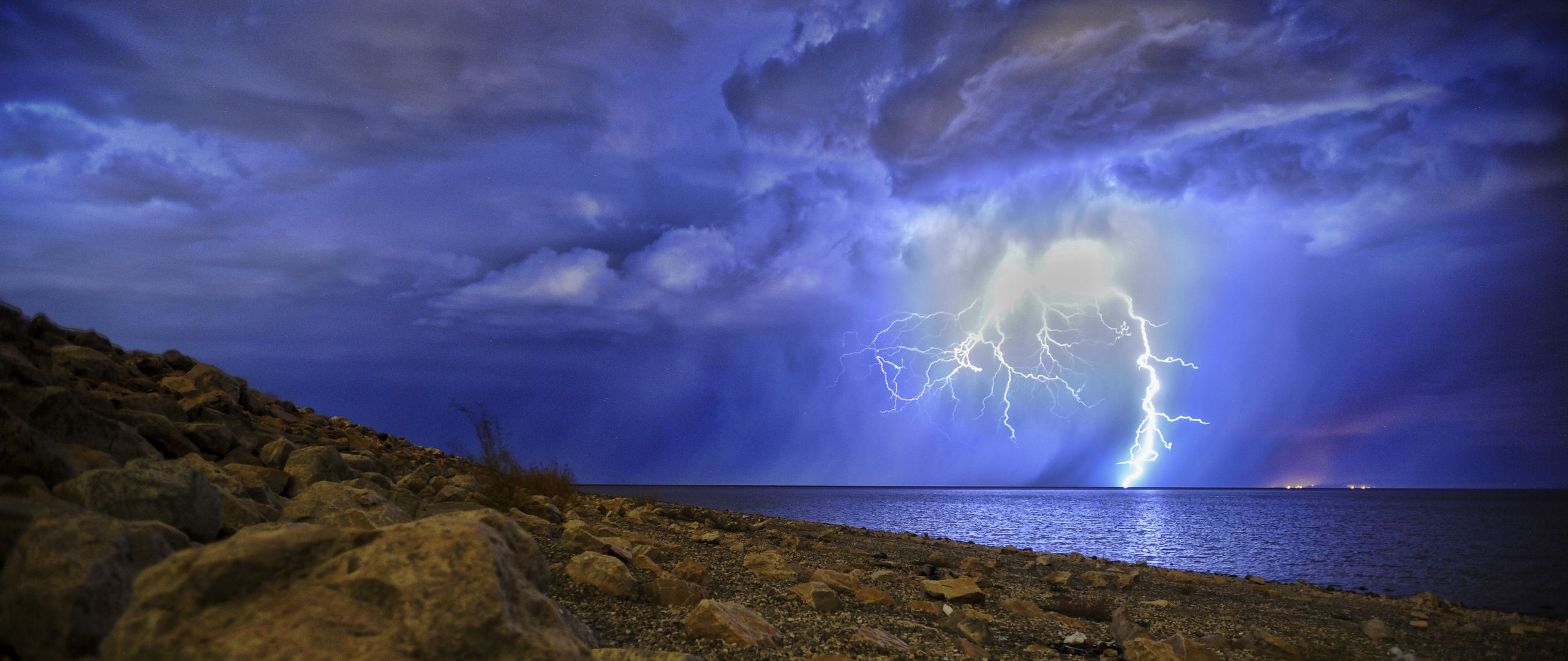 Download wallpaper 2560x1080 lightning, storm, lake, overcast, shore 