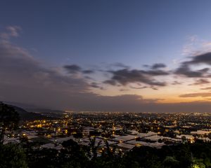 Preview wallpaper lights, city, buildings, roofs, sky, evening