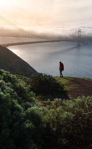 Preview wallpaper man, alone, hill, river, bridge, fog