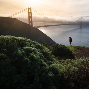 Preview wallpaper man, alone, hill, river, bridge, fog