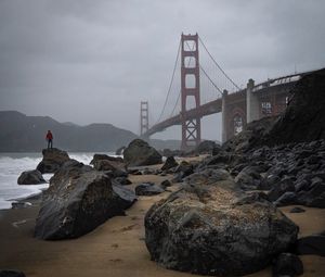 Preview wallpaper man, alone, rocks, waves, shore, bridge