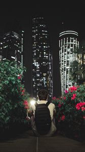 Preview wallpaper man, buildings, skyscrapers, bushes, flowers, night