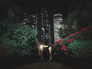 Preview wallpaper man, buildings, skyscrapers, bushes, flowers, night