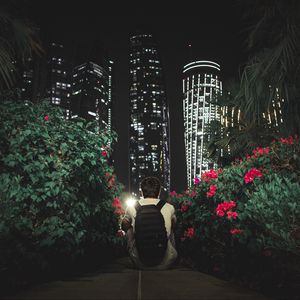 Preview wallpaper man, buildings, skyscrapers, bushes, flowers, night