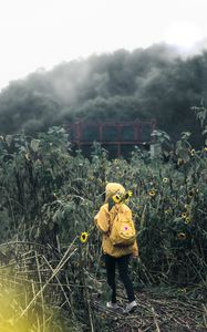 Preview wallpaper man, field, flowers, backpack, clouds, overcast