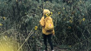 Preview wallpaper man, field, flowers, backpack, clouds, overcast