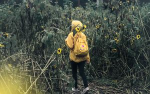 Preview wallpaper man, field, flowers, backpack, clouds, overcast