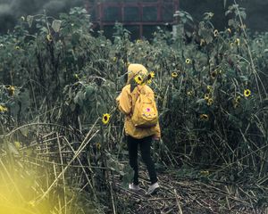 Preview wallpaper man, field, flowers, backpack, clouds, overcast