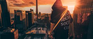 Preview wallpaper man, roof, city, sunset, aerial view, overview