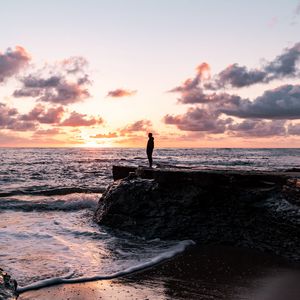 Preview wallpaper man, silhouette, alone, rock, sea, sunset