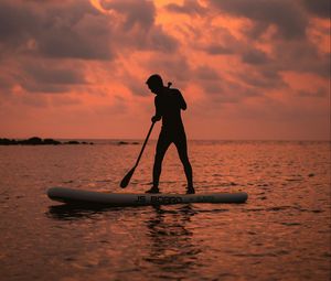 Preview wallpaper man, silhouette, alone, boat, water, sunset, dark