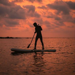 Preview wallpaper man, silhouette, alone, boat, water, sunset, dark