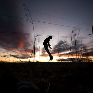 Preview wallpaper man, silhouette, jump, sunset, grass