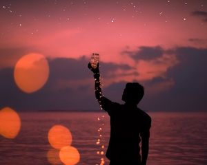 Preview wallpaper man, silhouette, stars, sea, shore, bank, glare