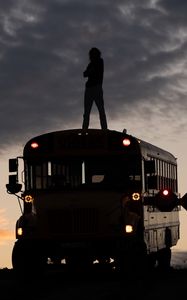 Preview wallpaper man, silhouette, triumph, alone, bus, sunset