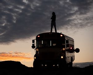 Preview wallpaper man, silhouette, triumph, alone, bus, sunset