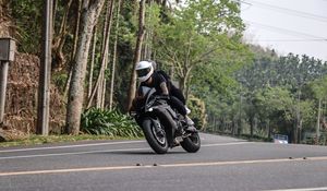 Preview wallpaper motorcycle, black, motorcyclist, speed, road, trees