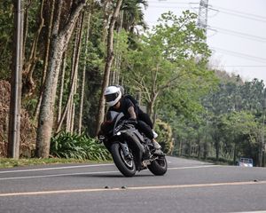 Preview wallpaper motorcycle, black, motorcyclist, speed, road, trees