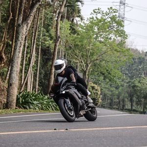Preview wallpaper motorcycle, black, motorcyclist, speed, road, trees