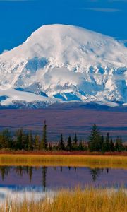Preview wallpaper mountain, snow-covered, top, autumn, trees, lake, clouds, reflections, haze, sky, blue, harmony