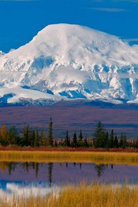 Preview wallpaper mountain, snow-covered, top, autumn, trees, lake, clouds, reflections, haze, sky, blue, harmony