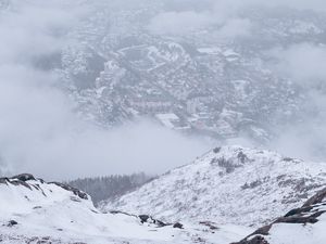 Preview wallpaper mountains, city, aerial view, fog, snow, clouds