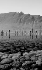 Preview wallpaper mountains, lake, bottom, stones, pilings, black and white