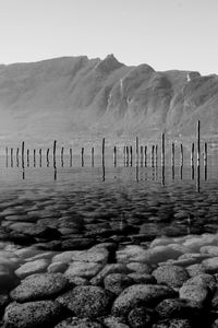 Preview wallpaper mountains, lake, bottom, stones, pilings, black and white