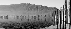 Preview wallpaper mountains, lake, bottom, stones, pilings, black and white