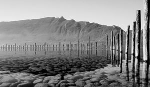 Preview wallpaper mountains, lake, bottom, stones, pilings, black and white