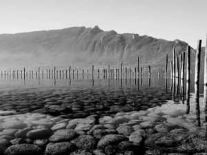 Preview wallpaper mountains, lake, bottom, stones, pilings, black and white