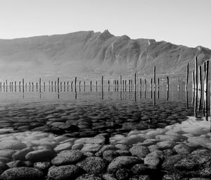 Preview wallpaper mountains, lake, bottom, stones, pilings, black and white