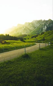 Preview wallpaper mountains, road, grass, sunlight, trees, landscape, switzerland