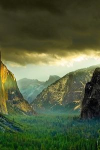 Preview wallpaper mountains, rocks, cloudy, gleam, coniferous, wood