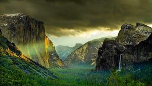 Preview wallpaper mountains, rocks, cloudy, gleam, coniferous, wood