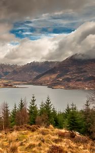 Preview wallpaper mountains, sky, lake, clouds, dense, wood, coniferous, birches, grass, faded, autumn, look, landscape