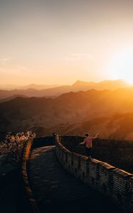 Preview wallpaper mountains, sunset, wall, building, people