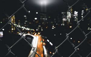 Preview wallpaper night city, fence, mesh, glare, blur