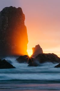 Preview wallpaper ocean, rock, sunset, rays, surf