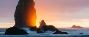 Preview wallpaper ocean, rock, sunset, rays, surf