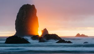 Preview wallpaper ocean, rock, sunset, rays, surf